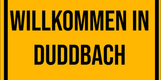Ein gelbes Schild mit der Aufschrift Willkommen in Duddbach